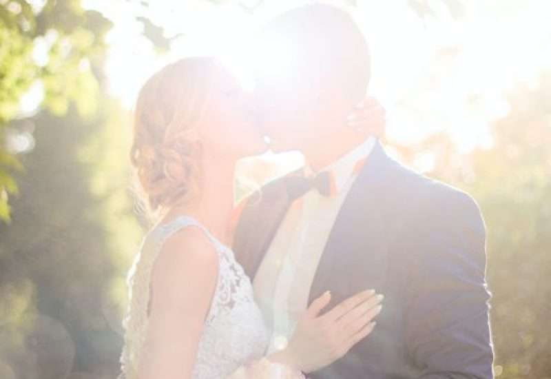 bride-and-groom-kissing-near-tree-against-the-sun-photo-1244700